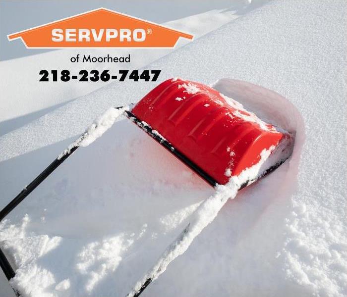 A large red snow removal device is being used to remove snow from a roof. 